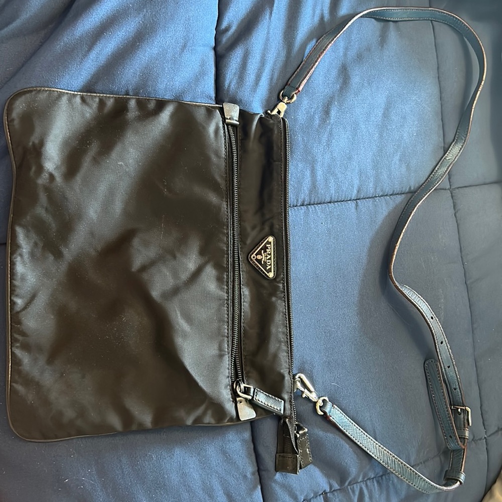 Black large pocketed Prada purse with a blue leather strap.